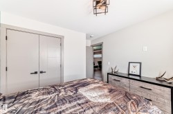 Bedroom featuring a contemporary ceiling light fixture, light gray walls, and light gray double closet doors with black hardware - 