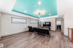 Spacious lower-level area featuring a tray ceiling with recessed lighting and a modern chandelier - 