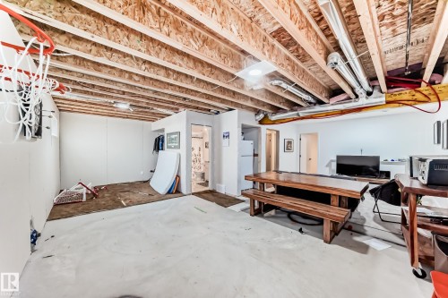 Unfinished basement with exposed wood joists and ductwork, featuring a partial wall enclosure housing a bathroom and a separate door leading to an additional space - 5263 47 Ave, Calmar, AB - Indoor Photo Showing Basement