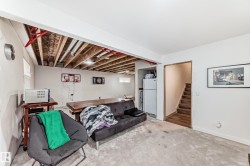 Unfinished basement space featuring exposed ceiling joists and utilities, painted white walls, and a light-colored carpeted floor - 