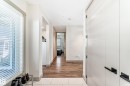 Bright entry area featuring a large window with white blinds, contemporary white doors with black hardware, recessed lighting, and wood-finish flooring transitioning to light-toned tile - 5263 47 Ave, Calmar, AB  - Indoor Photo Showing Other Room 