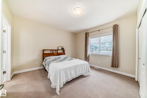 Neutral-toned bedroom featuring a large window, light beige wall paint, white baseboards, and neutral carpet flooring - 40 13808 155 Avenue, Edmonton, AB - Indoor Photo Showing Bedroom