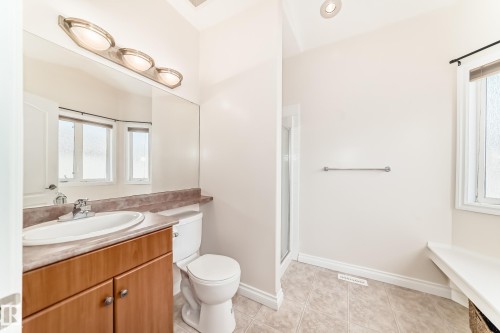 Bathroom featuring a wood-tone vanity with an oval sink, a countertop with integrated backsplash, and a large wall mirror - 40 13808 155 Avenue, Edmonton, AB - Indoor Photo Showing Bathroom
