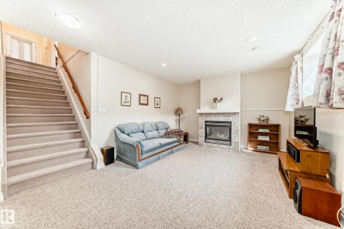 Spacious lower-level room featuring plush carpet flooring, a tiled fireplace with mantel, and recessed ceiling lighting - 40 13808 155 Avenue, Edmonton, AB - Indoor With Fireplace