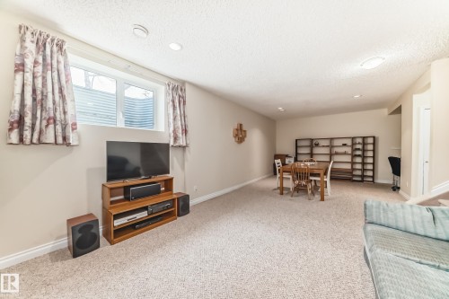Spacious lower-level room featuring soft carpeting, recessed lighting, and a large egress window with a window well - 40 13808 155 Avenue, Edmonton, AB - Indoor
