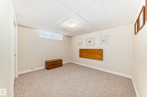 Carpeted room featuring a drop ceiling, light-colored walls, and a window with privacy covering - 40 13808 155 Avenue, Edmonton, AB - Indoor Photo Showing Other Room
