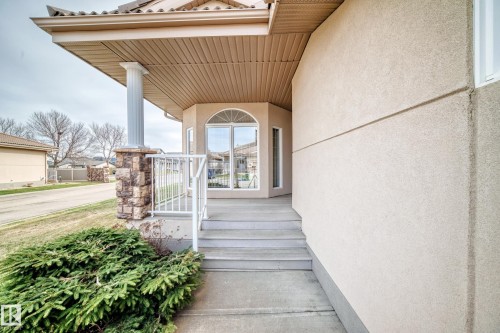 Stucco exterior with a covered entry, stone column detailing, and a multi-pane arched window - 40 13808 155 Avenue, Edmonton, AB - Outdoor With Exterior