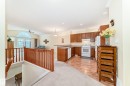 Open-concept living space featuring a kitchen with wood-finish cabinetry and white appliances, wood-finish flooring, and a breakfast bar - 40 13808 155 Avenue, Edmonton, AB  - Indoor Photo Showing Kitchen 