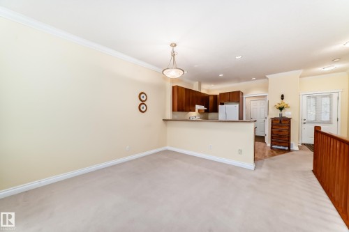Open-concept living space featuring light-colored carpeting and crown molding - 40 13808 155 Avenue, Edmonton, AB - Indoor Photo Showing Kitchen