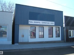 Commercial storefront building featuring a blue corrugated metal upper facade and white horizontal siding on the lower level - 