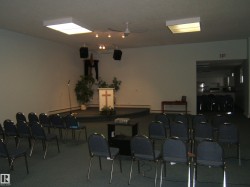 Carpeted room featuring a raised platform, recessed fluorescent lighting, and a ceiling fan - 