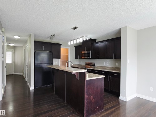 Kitchen featuring dark wood-finish cabinetry, light speckled countertops, and stainless steel appliances including a microwave and range - 21321 94 Avenue, Edmonton, AB - Indoor Photo Showing Kitchen With Upgraded Kitchen