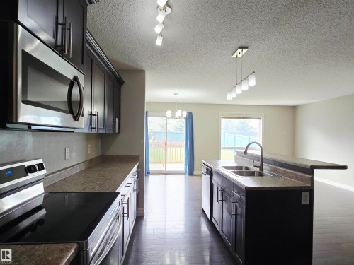 Kitchen featuring dark cabinetry with brushed nickel hardware, stainless steel appliances, and a double basin sink with a gooseneck faucet - 21321 94 Avenue, Edmonton, AB - Indoor Photo Showing Kitchen With Double Sink