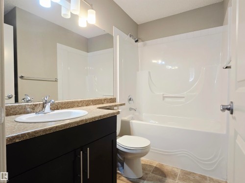 Bathroom featuring a dark wood-finish vanity with a light speckled countertop, an integrated sink, and a chrome faucet - 21321 94 Avenue, Edmonton, AB - Indoor Photo Showing Bathroom