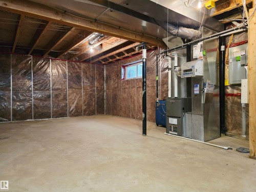 Unfinished lower level featuring exposed ceiling joists, insulated exterior walls, a concrete floor, utility systems, and a small window for natural light - 21321 94 Avenue, Edmonton, AB - Indoor Photo Showing Basement