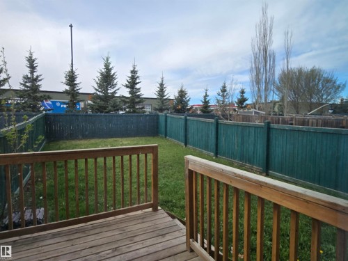 Expansive backyard featuring a wood deck with railings, lush green lawn, and full perimeter fencing - 21321 94 Avenue, Edmonton, AB - Outdoor