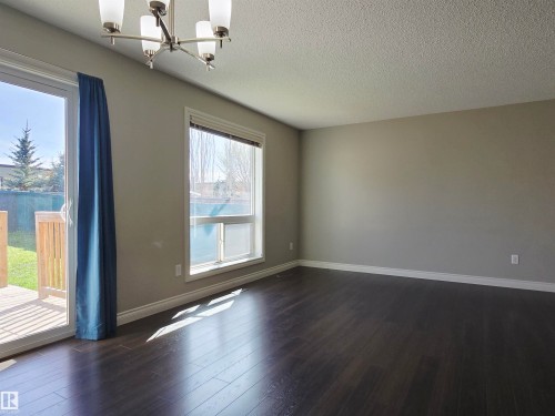 Spacious interior room featuring dark laminate flooring, a contemporary chandelier, and neutral wall tones - 21321 94 Avenue, Edmonton, AB - Indoor Photo Showing Other Room
