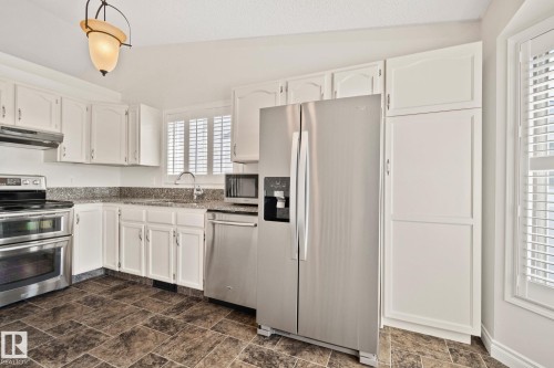 Kitchen featuring white cabinetry, stainless steel appliances, speckled countertops, a double oven range, and patterned floor tiling - 18903 70 Avenue, Edmonton, AB - Indoor Photo Showing Kitchen