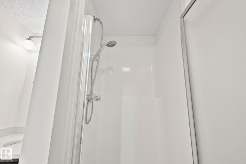 Shower enclosure featuring a handheld showerhead, white paneling, and a clear glass door - 18903 70 Avenue, Edmonton, AB - Indoor Photo Showing Bathroom