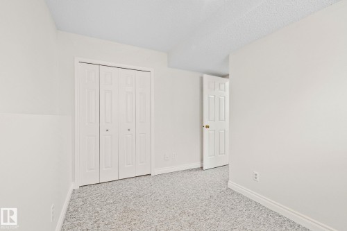 Neutral interior space featuring light-colored walls, patterned carpeting, and white trim - 18903 70 Avenue, Edmonton, AB - Indoor