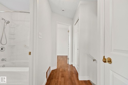 Interior hallway with wood-finish flooring, white walls, and white trim - 18903 70 Avenue, Edmonton, AB - Indoor