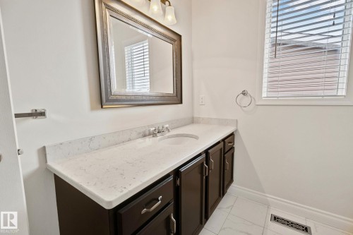 Vanity featuring a light countertop, integrated sink, and dark wood-finish cabinetry - 18903 70 Avenue, Edmonton, AB - Indoor Photo Showing Bathroom