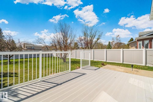 Spacious backyard featuring a light-toned composite deck with white railing and gate, a manicured lawn, and a two-tone privacy fence - 18903 70 Avenue, Edmonton, AB - Outdoor