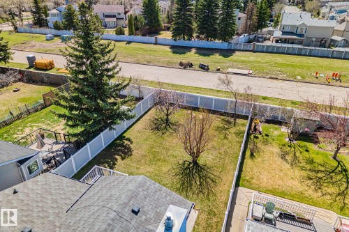 Expansive backyard featuring a manicured lawn, established trees, and a white privacy fence - 18903 70 Avenue, Edmonton, AB - Outdoor