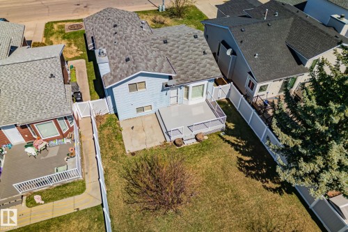 Rear exterior featuring a spacious wooden deck with white railing, a concrete patio, and a grass lawn - 18903 70 Avenue, Edmonton, AB - Outdoor