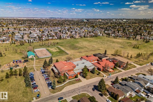 Residential neighborhood featuring a large green space, a school building with a parking area, and a playground with recreational structures - 18903 70 Avenue, Edmonton, AB - Outdoor With View