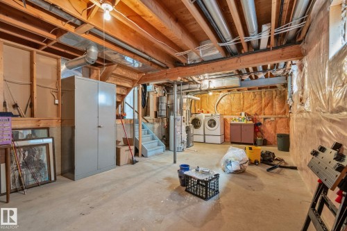 Unfinished basement offering exposed wood joists, concrete flooring, and a dedicated laundry area with washer and dryer units - 18903 70 Avenue, Edmonton, AB - Indoor Photo Showing Basement
