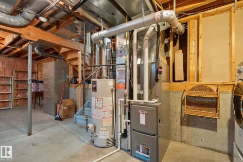 Utility area featuring a hot water heater, furnace, and exposed ductwork - 18903 70 Avenue, Edmonton, AB - Indoor Photo Showing Basement