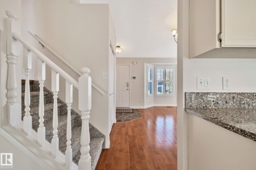 Inviting entryway featuring wood-finish flooring, a white paneled front door, and a bay window with louvered blinds - 18903 70 Avenue, Edmonton, AB - Indoor Photo Showing Other Room
