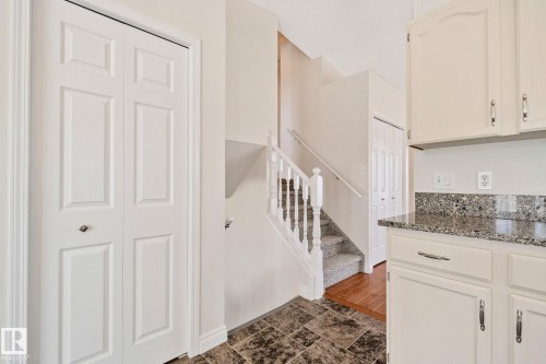 Kitchen perimeter featuring white cabinetry, polished hardware, and a speckled granite-style countertop - 18903 70 Avenue, Edmonton, AB - Indoor Photo Showing Other Room