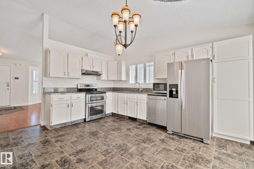 Kitchen featuring white cabinetry, stainless steel appliances, granite countertops, and large format tile flooring - 18903 70 Avenue, Edmonton, AB - Indoor Photo Showing Kitchen
