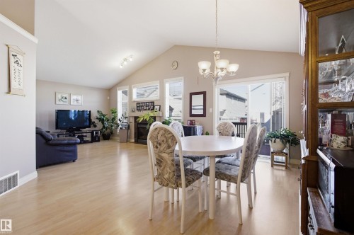 Open-concept living space featuring vaulted ceilings, wood-finish flooring, a fireplace, and multiple windows - 16204 48 Street, Edmonton, AB - Indoor Photo Showing Dining Room