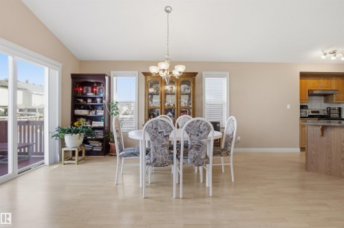 Dining area featuring light wood-finish flooring, a contemporary chandelier, and sliding glass doors opening to an outdoor deck - 16204 48 Street, Edmonton, AB - Indoor Photo Showing Dining Room