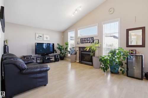 Spacious living area featuring light wood-finish flooring, a vaulted ceiling, and multiple windows with blinds - 16204 48 Street, Edmonton, AB - Indoor Photo Showing Living Room With Fireplace