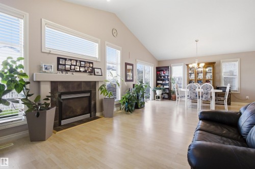 Vaulted ceiling main living area featuring light wood-finish flooring, a tile-surround fireplace with mantel, multiple large windows, and sliding glass door access - 16204 48 Street, Edmonton, AB - Indoor Photo Showing Living Room With Fireplace