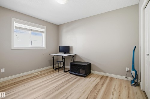 Neutral-toned room featuring light wood-finish flooring, a single window with white trim, and a built-in closet with a white door - 16204 48 Street, Edmonton, AB - Indoor