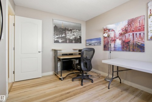 Versatile room featuring wood-finish flooring, neutral wall tones, and a white interior door - 16204 48 Street, Edmonton, AB - Indoor