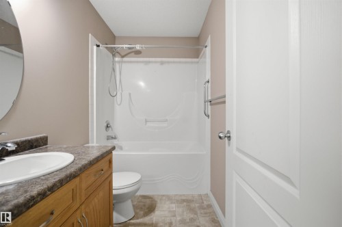 Bathroom featuring a single vanity with wood-finish cabinetry, a white oval sink, and a dark patterned countertop - 16204 48 Street, Edmonton, AB - Indoor Photo Showing Bathroom