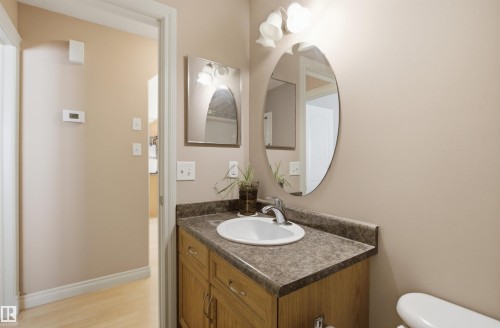 Bathroom vanity featuring a light wood-finish cabinet with double doors, an integrated white sink, a chrome faucet, and a brown patterned countertop - 16204 48 Street, Edmonton, AB - Indoor Photo Showing Bathroom