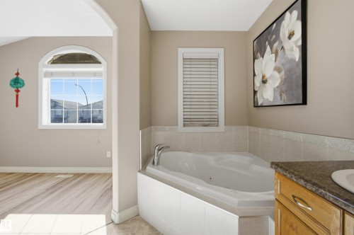 Tiled corner soaking tub featuring a single-handle chrome faucet - 16204 48 Street, Edmonton, AB - Indoor Photo Showing Bathroom