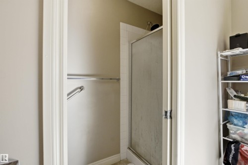 Shower enclosure featuring a framed frosted glass door, white tile surround, and chrome showerhead - 16204 48 Street, Edmonton, AB - Indoor Photo Showing Bathroom