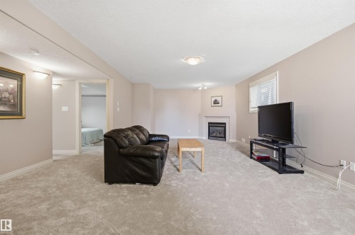 Spacious room featuring light-colored carpet flooring and neutral wall tones - 16204 48 Street, Edmonton, AB - Indoor With Fireplace