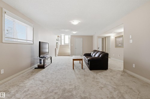 Spacious lower-level room featuring light-toned carpeting, neutral wall paint, a window with horizontal blinds, and recessed ceiling lighting - 16204 48 Street, Edmonton, AB - Indoor