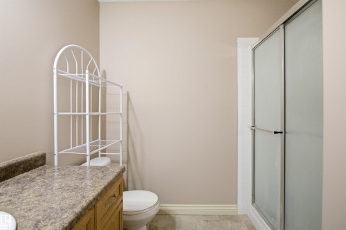 Bathroom featuring a glass-enclosed shower, wood-finish vanity cabinetry, and a stone-finish countertop - 16204 48 Street, Edmonton, AB - Indoor Photo Showing Bathroom