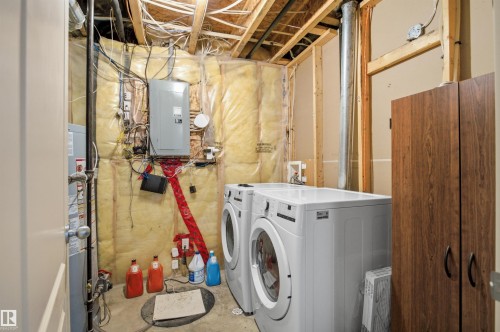 Utility area featuring exposed ceiling joists, wall insulation, and a wood-finish storage cabinet - 16204 48 Street, Edmonton, AB - Indoor Photo Showing Laundry Room