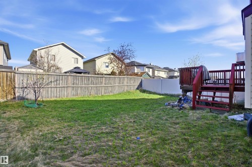 Expansive backyard featuring a red wood-stained deck with railing, a wooden privacy fence, and a young tree - 16204 48 Street, Edmonton, AB - Outdoor